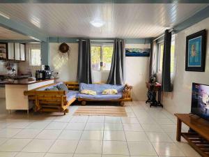 a living room with a couch and a kitchen at Meri Lodge Huahine (Mamado’s House) in Fare
