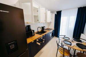 a kitchen with black cabinets and a table with chairs at Modern Loft One in Suceava