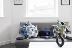 City-Centric Living Cozy 1-Bedroom Apartment في برادفورد: غرفة معيشة مع أريكة مع وسائد ونافذة