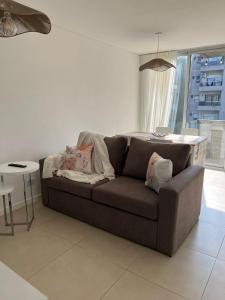 ein Wohnzimmer mit einem braunen Sofa und einem Tisch in der Unterkunft Confortable departamento en Castelar - Zona Céntrica. in Castelar