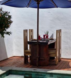 een tafel en stoelen met een parasol naast een zwembad bij The Sanctuary -Private pool villas in Gili Air