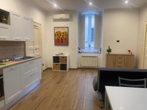 uma cozinha com armários brancos e piso em madeira em Via Rivocati 108 em Cosenza