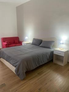 a bedroom with a large bed and a red couch at Via Rivocati 108 in Cosenza