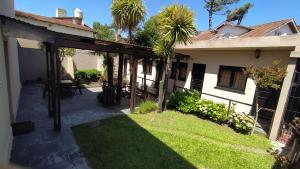 a patio of a house with a yard at Hotel Vireo in Villa Gesell