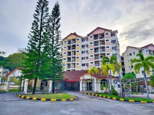 a large building with palm trees in front of it at Sunway Cozy Apartment near Lost World of Tambun in Ipoh