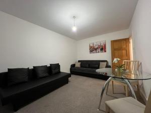 a living room with a black couch and a glass table at Entire Flat near Kings Cross in London