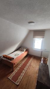 a bedroom with a bed and a window and a rug at Vikendica Vrtača- Odvraćenica in Novi Pazar