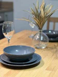 a wooden table with a blue bowl and two wine glasses at Large Apartment in City Centre, Leicester in Leicester