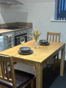 a wooden table with plates and wine glasses on it at Large Apartment in City Centre, Leicester in Leicester