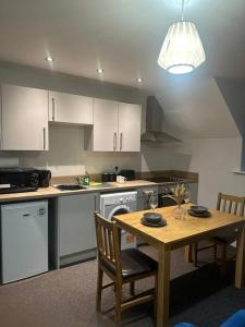 a kitchen with a wooden table and a table and chairs at Large Apartment in City Centre, Leicester in Leicester