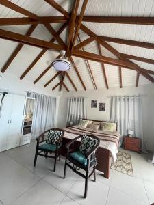 a bedroom with a large bed and two chairs at Studio Colline Nettle in Marigot