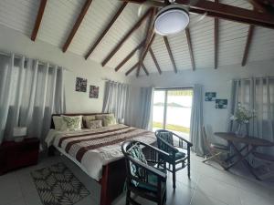 a bedroom with a bed with two chairs and a window at Studio Colline Nettle in Marigot