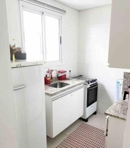 eine weiße Küche mit einem Waschbecken und einem Fenster in der Unterkunft Apartamento Próx Getúlio Vargas Duque e Nações in Bauru