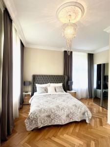 a bedroom with a large bed and a chandelier at Wienerwald Residenz in Baden