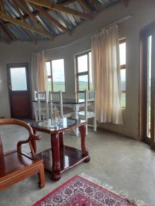 ein Wohnzimmer mit einem Tisch, Stühlen und Fenstern in der Unterkunft Kwa Flats-Emaweni in Lusikisiki