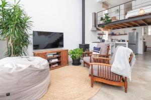 a living room with a flat screen tv and chairs at The Old Shop Loft apt in the heart of the village in Cape Town