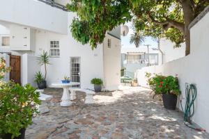 a courtyard with a white building and a bench at The Old Shop Loft apt in the heart of the village in Cape Town