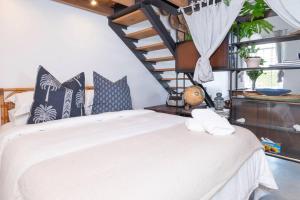 a bedroom with a white bed and a staircase at The Old Shop Loft apt in the heart of the village in Cape Town