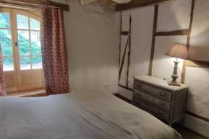 a bedroom with a bed with a dresser and a window at Le cottage des Acacias in Salignac Eyvigues
