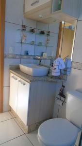 a bathroom with a sink and a toilet and a mirror at Apartamento aconchegante e completo no centro de Ponta Grossa - Paraná in Ponta Grossa