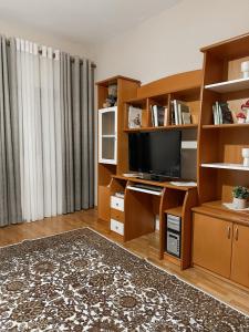 a living room with a tv and wooden shelves at Villa Malo Guesthouse in Korçë