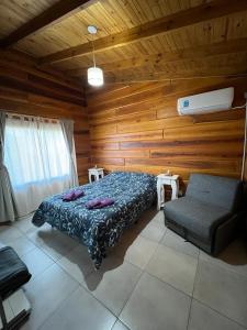 a bedroom with a bed and a couch and wooden walls at Cabañas Puesta del Sol in Villa Yacanto