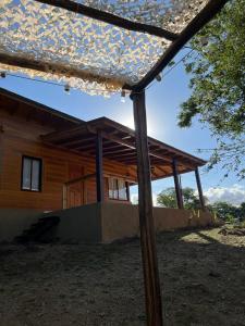 a wooden house with a roof and a porch at Cabañas Puesta del Sol in Villa Yacanto