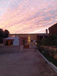 a house with a sunset in the sky at Mariella House in Fasano