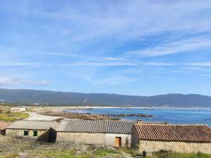 um grupo de edifícios na costa de uma massa de água em Casa rural de uso turístico Playa de Carnota em Canedó