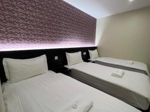 two beds in a small room with white sheets at Pekan Auto City Budget Hotel in Pekan