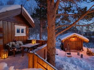 a cabin in the snow with a picnic table and a tree at Malangen Lodge in Mestervik