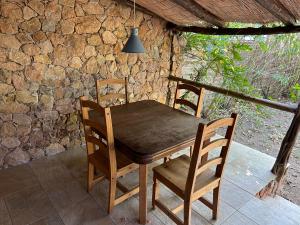a wooden table and chairs on a porch with a stone wall at A casa di maria in Figari