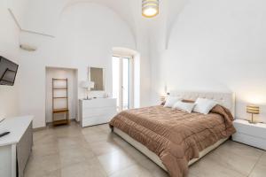 a white bedroom with a large bed and a desk at Le Bianche Suites Ostuni in Ostuni