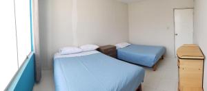 two beds in a small room with blue sheets at Sacasa Summer in Los Cerrillos