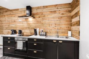 uma cozinha com armários pretos e uma parede de madeira em Harrow Lodge - Anfield Apartments em Liverpool