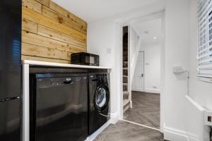 uma máquina de lavar e secar roupa num quarto com uma parede de madeira em Harrow Lodge - Anfield Apartments em Liverpool