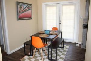 a dining room with a black table and orange chairs at Birchwood Place in Little Rock