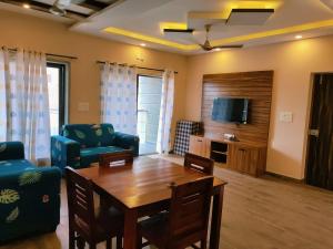 Luxury 2BHK Apartment Near Candolim في Nerul: غرفة معيشة مع طاولة وكراسي وتلفزيون