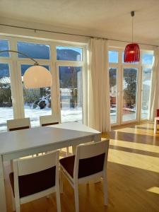 a dining room with a white table and chairs and windows at FLORES, Ferienhaus oder Doppelzimmer, im Grünen, 5 Gehminuten ins Zentrum, Parkplatz, zero emissions in Bad Ischl
