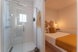 a bathroom with a shower and a bed with a glass door at Apartamento Turístico KHöALA HOME in Mérida