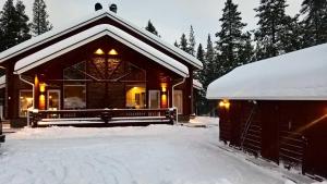una cabaña de madera con nieve en el suelo junto a un garaje en Unelmasäleikkö 2 en Kittilä