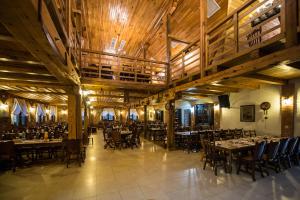 a dining room with tables and chairs and wooden ceilings at Hanul Moara cu Noroc in Ineu