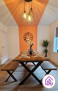 a dining room table with plates and wine glasses at Redcliffe House, Stylish House Close To Designer Outlet in Swindon