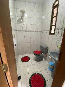 La salle de bains est pourvue de toilettes et de tapis rouges. dans l'établissement Recanto mato verde, à Caraguatatuba
