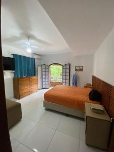 um quarto com uma cama laranja e uma janela em Recanto mato verde em Caraguatatuba