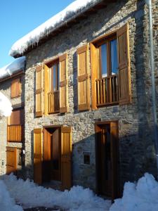 a building with wooden windows and snow on the ground at GITE DU TREUIL in Ignaux