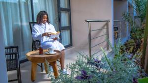 a woman sitting on a balcony reading a book at The Telescope Boutique Lodge in Victoria Falls