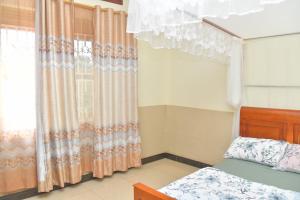 een slaapkamer met een bed en een raam met gordijnen bij Makindye Kizungu Holiday Villa in Makindye