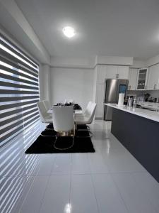a white kitchen with a table and white chairs at Brand New 4 bedroom Villa by Hamilton Airport! in Hamilton