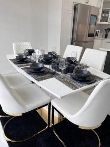a white dining table with white chairs and glasses on it at Brand New 4 bedroom Villa by Hamilton Airport! in Hamilton
